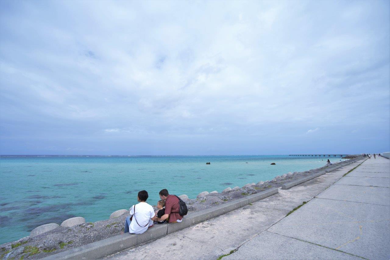 青い海を前に座っているタサン志麻さん